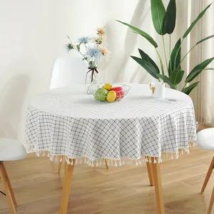Nappe ronde à carreaux blancs avec pompons sur une table à manger en bois moderne