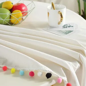 Linen table runner with colorful pompom trim and minimalist Nordic home decor style