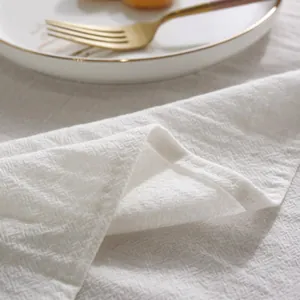 Macro detail of high-quality white cotton tablecloth with textured weave and hemmed edges
