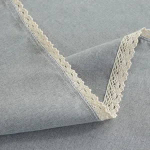 Detail van grijs waterdicht linnen tafelkleed met witte gehaakte kant en textuur