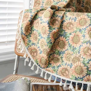 Katoenen jacquard deken met zonnebloempatroon en kwastjes op een rotan stoel
