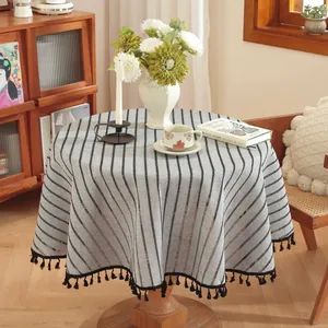 Close-up of minimalist striped round tablecloth with elegant black tassel fringe detail