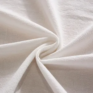 Macro detail of white cotton fabric showing natural woven texture and soft pleats