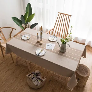 Dettaglio tovaglia in lino grigio con ricami bianchi e bordi decorati con nappe
