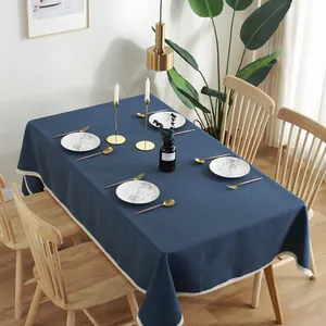 Detail van donkerblauw linnen tafelkleed met witte kanten rand op houten eettafel