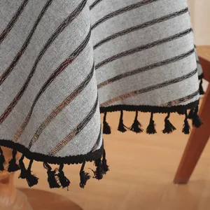 Detailed macro view of gray striped tablecloth fabric with elegant black tassel fringe