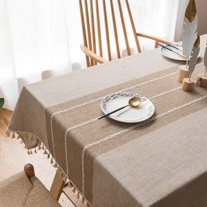 Dettaglio tovaglia in cotone e lino grigio con nappe eleganti e ricamo a croce