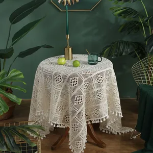 Tovaglia in pizzo beige lavorata a mano con frange su tavolo in legno scuro