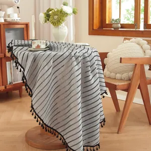 Detail of grey striped linen tablecloth featuring decorative black tassels on the edge