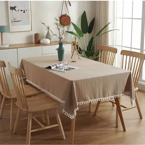 Minimaal rechthoekig kaki tafelkleed met witte pompon franjes voor een warm wooninterieur