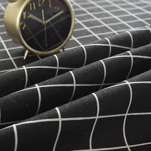 Close-up of black and white checkered linen tablecloth fabric texture with a vintage clock