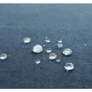 Macro-opname van waterdruppels op waterdichte donkergrijze linnen tafelkleedstof