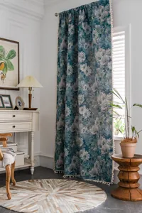 Detail van donkerblauw bohemien gordijn met witte bloemmotieven en witte pompon-kwastjes decor
