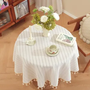 Close-up of bohemian round tablecloth with striped pattern and beige pom-pom fringe