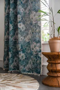 Close-up van blauw bloemengordijn met witte franjes in een gezellige slaapkamer