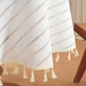 Detail of striped cotton linen tablecloth featuring handmade tassel edges and woven texture