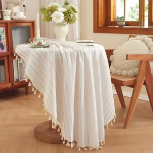 Detail of round striped tablecloth with tassel edges on a wooden table in home setting