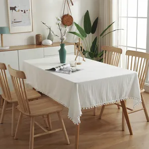 Solid white rectangular tablecloth with decorative pom-pom fringe and natural linen texture