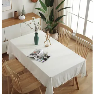 Close-up of white washed cotton tablecloth featuring decorative pom-pom fringe edges