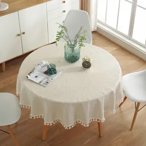 Détail d'une nappe ronde en lin beige avec de délicats pompons à franges pour la maison