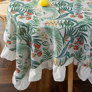 Detail of round cotton linen tablecloth with tropical leaf print and ruffled edges