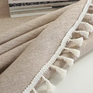 Detail van linnen tafelkleed met elegante witte kwastjes en een natuurlijke weving