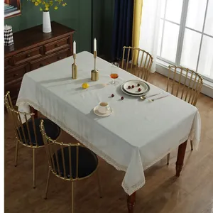 Close-up of elegant beige linen tablecloth featuring intricate lace edges on a wooden table
