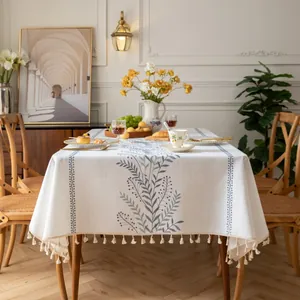 Dettaglio tovaglia in lino con ricamo botanico blu e nappe con frange color crema