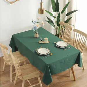 Macro detail of dark green cotton tablecloth showing texture and natural drape on a table