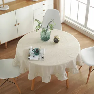 Detail of a beige cotton linen round tablecloth with elegant ruffle edges and soft texture