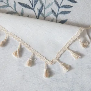 Dettaglio tovaglia in lino con ricamo di foglie blu e bordi con nappe beige eleganti