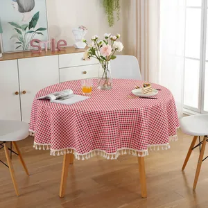 Detail of red and white checkered round tablecloth with decorative white pom-pom tassels