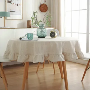 Detail of round beige linen tablecloth with wide ruffled edges and natural texture