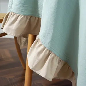 Detail view of mint green tablecloth with ruffled edges and natural cotton linen texture