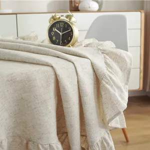 Detail of beige cotton linen tablecloth featuring vintage ruffled edges and rustic texture