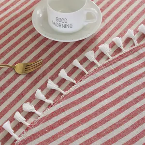 Close-up of red striped cotton linen tablecloth with elegant white fringe tassel detail
