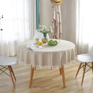 Detail of striped round tablecloth featuring cotton-linen texture and white tassel edges