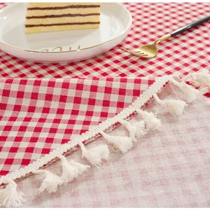 Close-up of pink gingham cotton linen tablecloth with white tassels and dining decor