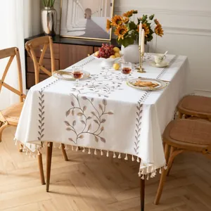 Dettaglio del ricamo a vite e nappe su una tovaglia rettangolare in lino beige