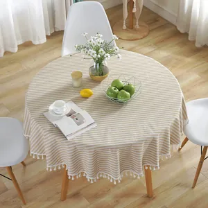 Detail of round cotton linen tablecloth with beige stripes and white tassel fringe