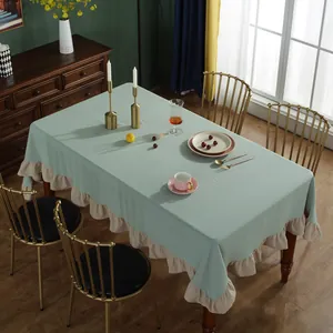 Detailopname van het saliegroene tafelkleed met beige ruches op een houten tafelblad