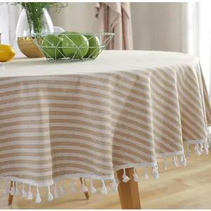 Detail of round striped tablecloth with white rope tassels on beige cotton linen fabric