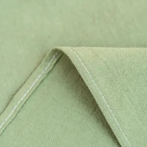 Macro-opname van lichtgroen katoenen tafelkleed met witte stiksels aan de rand