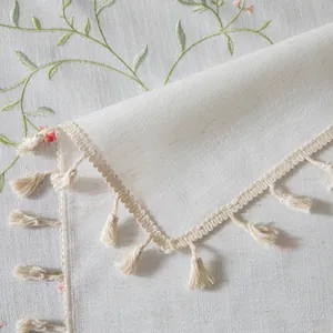 Dettagli del ricamo floreale e nappe su una tovaglia in misto cotone e lino
