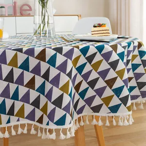 Detail of geometric triangle pattern tablecloth with white cotton tassels and linen texture