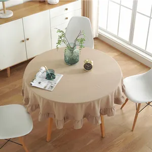 Detailed overhead view of a round beige tablecloth with vintage ruffles on the edges