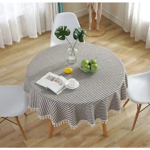 Detail of round cotton linen tablecloth with gray stripes and white tassel trim