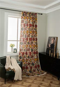 Detail of bohemian cotton linen curtain with sunflower prints and white pompom fringes