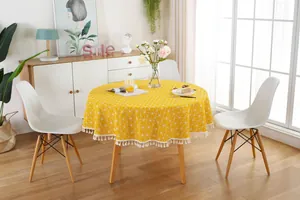 Detail of yellow round tablecloth with geometric grid pattern and white tassel fringe