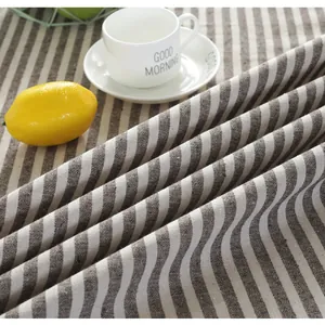 Close-up of rustic coffee and cream striped linen tablecloth with tassels and natural texture